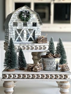 a white table topped with christmas decorations and a small barn shaped house on top of it