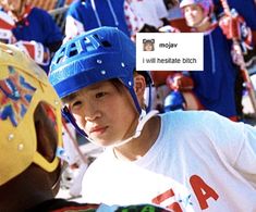 a young boy wearing a blue helmet talking to another person