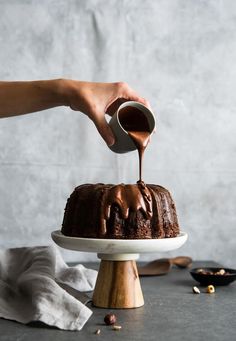 a person drizzling chocolate icing onto a cake