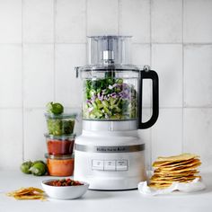 a blender filled with lots of food on top of a counter next to some tortilla chips