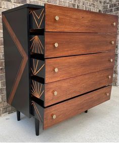 a black and brown chest of drawers sitting next to a brick wall