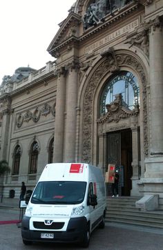 a white van parked in front of a large building with an ornate doorway and entrance