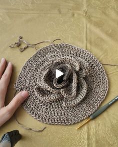 a crocheted hat being worked on by someone's hand with scissors and yarn