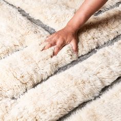 a person reaching for something on top of a fluffy white blanket that is covering the floor