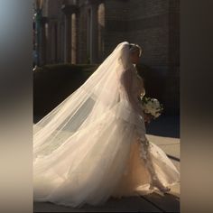 a woman in a wedding dress is walking down the street with her veil over her head