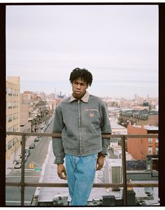 a young man standing on top of a building next to a parking lot and looking at the camera