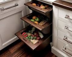 a kitchen with white cupboards and drawers filled with fruits, vegetables and veggies