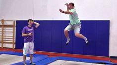 a man jumping in the air while playing frisbee with another man standing behind him