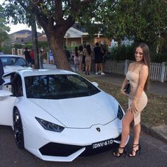 a woman standing next to a white sports car