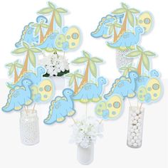 blue and yellow dinosaur cupcake toppers in a vase with white flowers on the table