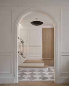 an open doorway leading to a hallway with white walls and checkered tile flooring