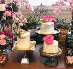 a table topped with cakes and flowers on top of wooden trays next to each other