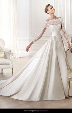 a woman in a white wedding dress standing next to a chair with her hands on her hips