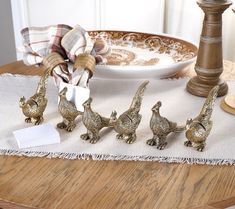 four brass figurines are sitting on a table with a place card holder in front of them