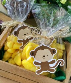 two bags filled with yellow and brown candy sitting on top of a wooden box next to flowers