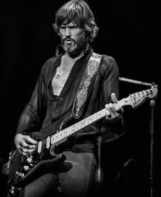 a man with long hair playing an electric guitar