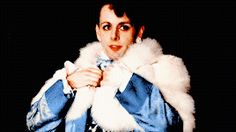 a woman wearing a blue jean jacket and white fur stole around her neck, posing for the camera