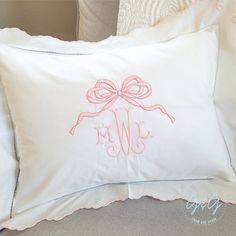 a white pillow with a pink bow and monogrammed letters on the front is sitting on a couch