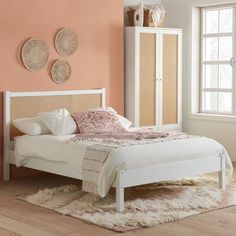 a white bed sitting in a bedroom on top of a hard wood floor next to a window