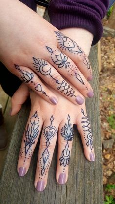 two hands with tattoos on them sitting on a wooden bench next to another hand that has leaves and arrows tattooed on it