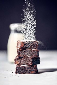 a stack of brownies sitting next to a bottle of milk