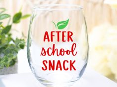 a glass with the words after school snack on it next to a potted plant