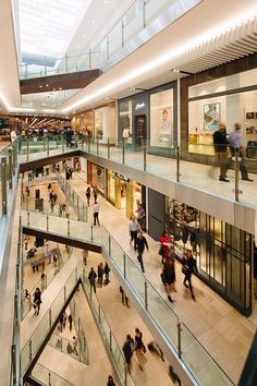 an indoor mall with people walking around and on the escalators in front of them