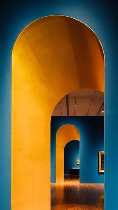 an archway leading into a room with blue walls and wood flooring on either side