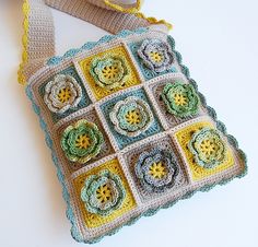 a crocheted granny bag hanging on a white table with a yellow ribbon around it