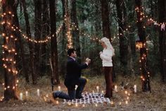 a man kneeling down next to a woman in the woods