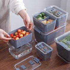 a woman is picking up some fruits and vegetables from the container on the table with other containers