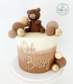 a teddy bear on top of a cake with gold decorations and the words oh baby