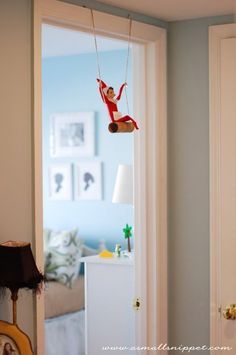 a person on a swing suspended from the ceiling in a room with a door open