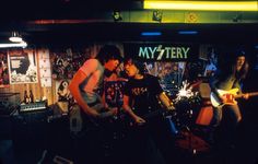 three young men are playing guitars in a music store while one man is singing into the microphone