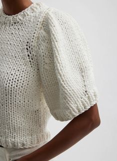 a woman is wearing a white knit sweater