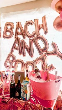 a party table with balloons, champagne bottles and pink buckets filled with confetti