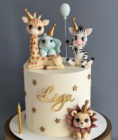 a birthday cake with animals and balloons on it's top tier, including a giraffe