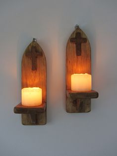 two wooden wall sconces with lit candles on them