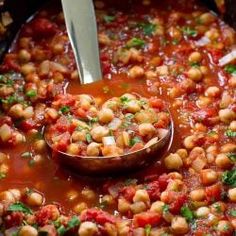 a pot filled with beans and garnish on top of a wooden spoon in it