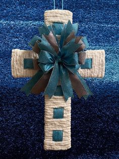 a cross hanging on a blue carpet with a green bow and ribbon around the center