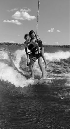 two women riding water skis while being pulled by a sailboat in the ocean