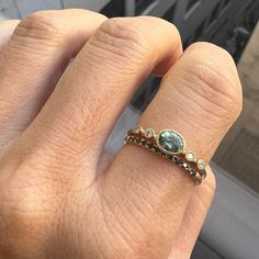 a woman's hand with a ring on it that has a blue stone in the middle