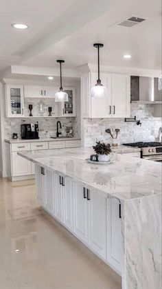 a large kitchen with marble counter tops and white cabinets