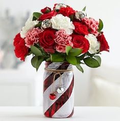 red and white flowers are in a striped mason jar with candy canes on the table