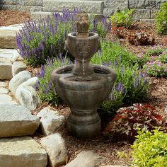 a water fountain surrounded by rocks and flowers