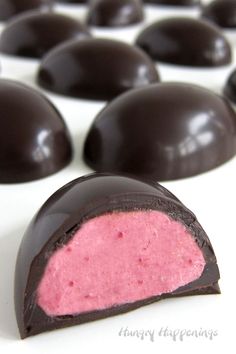 chocolate covered candy sitting on top of a white table with pink and black candies