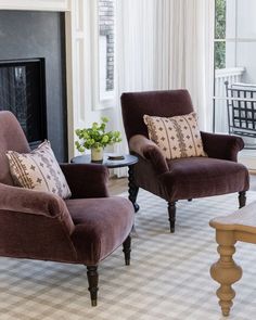 a living room with two chairs and a coffee table in front of a fire place