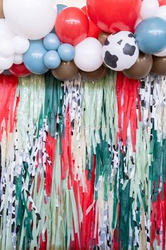 balloons and streamers are hanging from the ceiling in front of a curtain with cow print on it