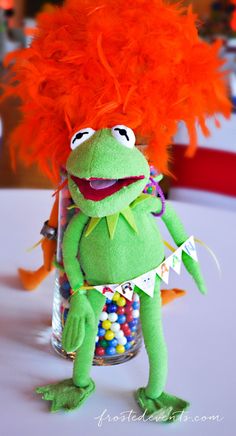 the muppet is wearing an orange wig and standing next to a jar full of candy