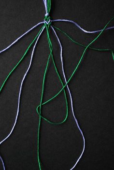 the string has been tied together to make an ornament with green and white thread